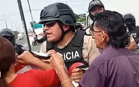 Miembros de la Policía Nacional retiran una pancarta que sostenían moradores de la avenida Cacique Tomalá durante una protesta.