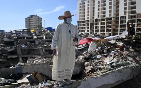 Un sacerdote permanece de pie sobre los escombros de un edificio destruido por los terremotos del 24 de junio en Caraballeda, Venezuela, el 17 de julio de 2026.