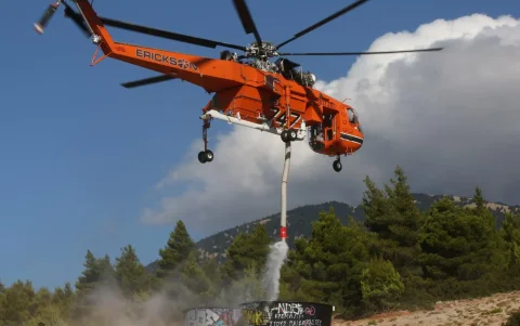 Un helicóptero de extinción de incendios llena su depósito de agua durante un incendio forestal en los alrededores de Megara, Ática, Grecia.