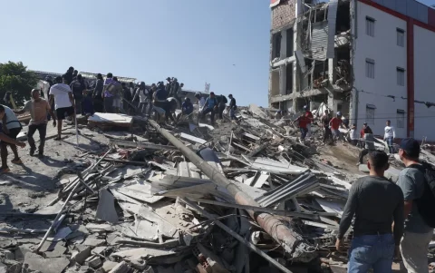 Personas caminan sobre los escombros de un edificio colapsado este lunes, en Cali (Colombia).