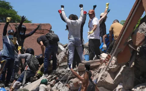 Personas reaccionan durante la búsqueda de sobrevivientes entre los escombros de una edificación colapsada.