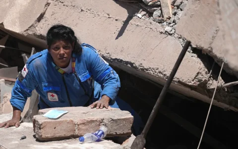 Una integrante de la Cruz Roja de Colombia busca entre los escombros de una edificación.