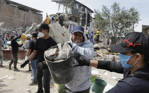 Voluntarios realizan una cadena humana para sacar escombros de edificaciones destruidas por el terremoto de magnitud 7,4.