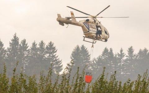 Un helicóptero de la policía con un cubo de agua vuela en apoyo a los bomberos que luchan contra el incendio forestal en Sourbrodt, Bélgica, el 17 de agosto de 2026.