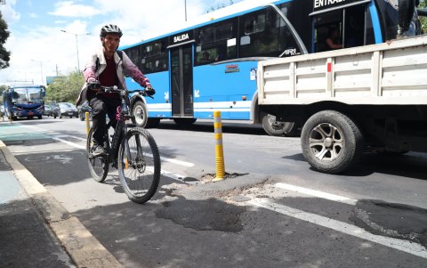Ciclistas enfrentan baches, gravilla y rutas deterioradas en Quito, mientras vehículos invaden ciclovías y dificultan su circulación segura por la ciudad.