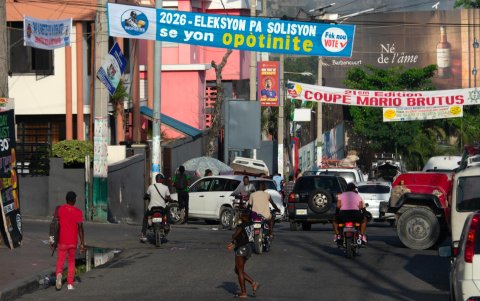 Personas circulan por una calle con publicada política este jueves, en Puerto Príncipe (Haití).