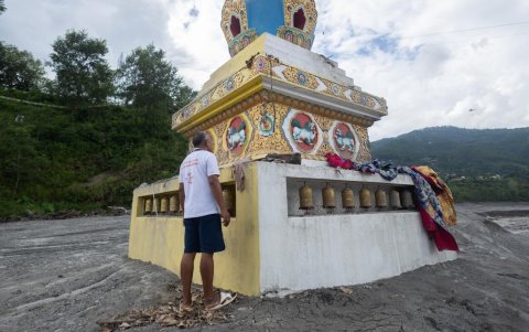 Un hombre limpia el monumento al Lord Gautama Buda afectado por una inundación glacial cerca de la frontera entre Nepal y China.