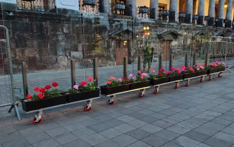 Las jardineras con geranios están sobre una estructura de vidrio.
