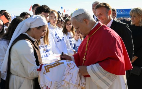 El papa León XIV (c) firma una camiseta a una monja junto al presidente francés, Emmanuel Macron.