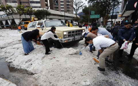 Ciudadanos colaboraron en el retiro del hielo acumulado sobre los vehículos que quedaron cubiertos por la fuerte granizada registrada en Quito.