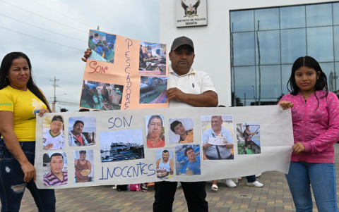 Familiares de los tripulantes de las embarcaciones 'X Siempre Don Carlos' y 'Karla Franccesca', posan con un cartel afuera de la Unidad de Vigilancia Comunitaria