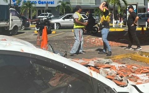Personas observan un vehículo afectado por los restos de un edificio en Ciudad de Panamá, tras un terremoto de magnitud 7,7 que sacudió el país este viernes 9 de octubre.