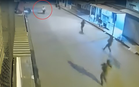 En un video de cámara de seguridad se observa a unos uniformados corriendo detrás de sujetos en motocicleta.