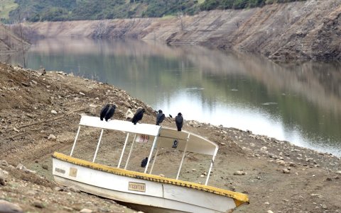 Varios gallinazos descansan sobre un bote varado, lejos de la actual orilla del agua del embalse Mazar.