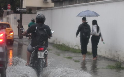 Varios ciudadanos caminaron descalzos por las aceras de Guayaquil para evitar que el agua acumulada por las intensas lluvias empapara aún más su calzado.
