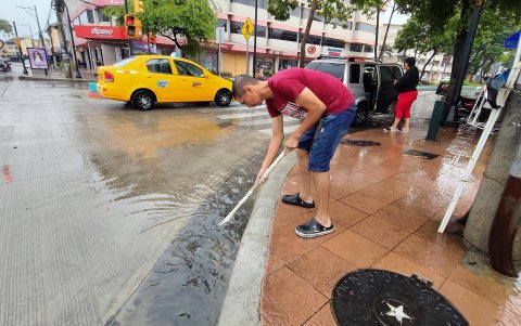 En La Alborada, un ciudadano intenta destapar una rejilla de drenaje obstruida para facilitar la evacuación del agua acumulad