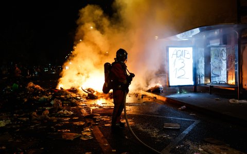 Un bombero francés interviene ante barricadas en llamas en una calle.