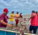 Trabajadores al pie del mar muestran la red dañada y llena de las jaibas.