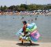 AME640. RÍO DE JANEIRO (BRASIL), 26/12/2025.- Una mujer vende flotadores y juguetes para la arena en la playa del lago artificial 'Piscinão de Ramos' este viernes, en Río de Janeiro (Brasil). El Instituto Nacional de Meteorología de Brasil (Inmet) emitió este viernes una alerta roja para todo el territorio de los estados de São Paulo y Río de Janeiro por una ola de calor que, previsiblemente, se prolongará hasta el lunes. EFE/ Antonio Lacerda
