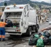 Una ciudadana reclama por el incremento en la tasa de basura mientras sostiene su planilla frente a un punto de recolección.
