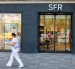 Una persona pasa al pide de una tienda de SFR.