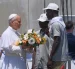 El papa León XIV recibe flores de dos voluntarios para protagonizar una ofrenda floral en el mar en recuerdo de los migrantes muertos.
