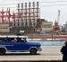 Un auto viejo de transporte colectivo al pasar frente a una planta flotante de generación eléctrica en el puerto de La Habana (Cuba).