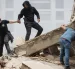 Personas caminan entre los escombros de edificios derrumbados en La Guaira tras los terremotos en Venezuela.