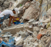 Una persona busca entre los escombros de edificios destruidos por terremotos en Caraballeda.