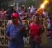 Campesinos sostienen banderas y velas en una vigilia en rechazo al decreto ejecutivo que ordena la clausura de los cementerios comunitarios.