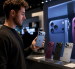 Una persona sostiene uno de los nuevos modelos de iPhone mientras observa otros dispositivos exhibidos en una tienda de tecnología.