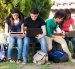 Group of teenagers social networking using several tech devices in high school