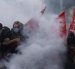 Estudiantes de secundaria permanecen en medio de gases lacrimógenos mientras estallan enfrentamientos entre estudiantes y la policía antidisturbios.