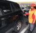 Una trabajadora de una gasolinera despacha el combustible para un carro.