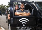 Roman Reyna (L) owner of JFK transportation and Kevin Watson (R), president of JFK transportation, pose with one of their company vans equipped as a mobile Wifi Hotspot to help students access internet to remotely attend their classes, September 16, 2020, in Santa Ana, California. - A minivan with a Wi-fi router attached to the dashboard and a satellite antenna on the roof is helping 200 disadvantaged students in Santa Ana, close to Los Angeles, cope with the rigors of distance learning during the coronavirus pandemic. (Photo by VALERIE MACON / AFP)