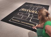 Una visitante interactúa con la rayuela-alfombra que reproduce la portada de la primera edición de Rayuela publicada en 1963 por Editorial Sudamericana.