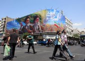 Iraníes pasan frente a una gran valla publicitaria con los difuntos líderes supremos iraníes, los ayatolás Ruhollah Jomeini y Ali Jameneí, en una calle de Teherán, Irán.
