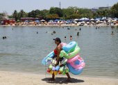 AME640. RÍO DE JANEIRO (BRASIL), 26/12/2025.- Una mujer vende flotadores y juguetes para la arena en la playa del lago artificial 'Piscinão de Ramos' este viernes, en Río de Janeiro (Brasil). El Instituto Nacional de Meteorología de Brasil (Inmet) emitió este viernes una alerta roja para todo el territorio de los estados de São Paulo y Río de Janeiro por una ola de calor que, previsiblemente, se prolongará hasta el lunes. EFE/ Antonio Lacerda