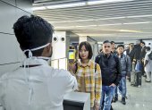 Un hombre usa una cámara termográfica para controlar la cabeza de las personas en el Aeropuerto Internacional Netaji Subhash Chandra Bose en Kolkata, siguiendo las recomendaciones del Ministerio de salud.