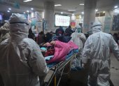 In this photo taken on January 25, 2020, medical staff wearing protective clothing to protect against a previously unknown coronavirus arrive with a patient at the Wuhan Red Cross Hospital in Wuhan. - The number of confirmed deaths from a viral outbreak in China has risen to 54, with authorities in hard-hit Hubei province on January 26 reporting 13 more fatalities and 323 new cases. (Photo by Hector RETAMAL / AFP)