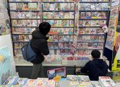 Dos personas observan algunos de los títulos de manga más populares del momento, que son también adaptados a series de anime, en una tienda de Tokio, Japón.