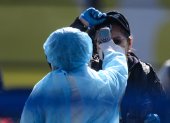 Workers in protective clothes measures the body temperature of a passenger disembarking from the Diamond Princess cruise ship, in quarantine due to fears of new COVID-19 coronavirus, at Daikoku pier cruise terminal in Yokohama on February 21, 2020. - Hundreds of people have been allowed to leave the ship after testing negative for the disease and many have returned to their home countries to face further quarantine. (Photo by Philip FONG / AFP)