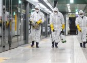 Workers wearing protective gear spray disinfectant as part of preventive measures against the spread of the COVID-19 coronavirus, at a subway station in Seoul on February 28, 2020. - K-pop megastars BTS on February 28 cancelled four concerts they were due to hold in Seoul in April, their agency said, as the coronavirus outbreak spreads in South Korea. The country has so far confirmed more than 2,000 cases of the novel coronavirus, by far the largest national total outside China, the origin of the disease. (Photo by - / YONHAP / AFP) / - South Korea OUT / REPUBLIC OF KOREA OUT  NO ARCHIVES  RESTRICTED TO SUBSCRIPTION USE
