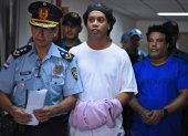 Ronaldinho (C) y su hermano, Roberto Assis (d) fueron detenidos el viernes y el sábado se les dictó orden de prisión. Permanecen en el edificio de una función judicial.