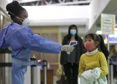 NAIROBI. Un trabajador de la salud de Kenia examina a una niña que arriba en un vuelo desde china en el Aeropuerto Internacional "Jomo Kenyatta".