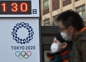 Transeúntes japoneses pasan por una de las edificaciones de Tokio que llevan la cuenta regresiva del inicio de los Juegos Olímpicos 2020.

 OLY-2020-TOKYO-HEALTH-VIRUS