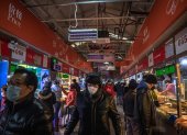Las personas que usan máscaras protectoras visitan un mercado en Beijing, China