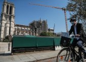 Paris (France), 09/04/2020.- A man wearing a protective facial mask rides his bicycle by the Notre Dame Cathedral, in Paris, France, 09 April 2020. France is under lockdown in an attempt to stop the spread of the SARS-CoV-2 coronavirus causing the COVID-19 disease. A year ago, on 15 April 2019, the 850-year-old Notre-Dame Cathedral of Paris suffered a devastating fire. Some 500 firefighters managed to prevent the entire cathedral from being reduced to ashes, although its celebrated spire has been destroyed. (Incendio, Francia) EFE/EPA/MOHAMMED BADRA