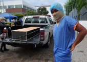 Un hombre se pone un traje protector fuera de la morgue del Hospital General Guasmo Sur para identificar a su pariente que murió del coronavirus.