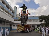 Fireman Henry Garcia stands on the top of a fire engine"s ladder from where he plays the trumpet to lift the spirits of personnel of the health sector and patients during the novel coronavirus COVID-19 pandemic, at the emergency door of the Carlos Andrade Marin Hospital in Quito, on April 18, 2020. (Photo by Rodrigo BUENDIA / AFP)